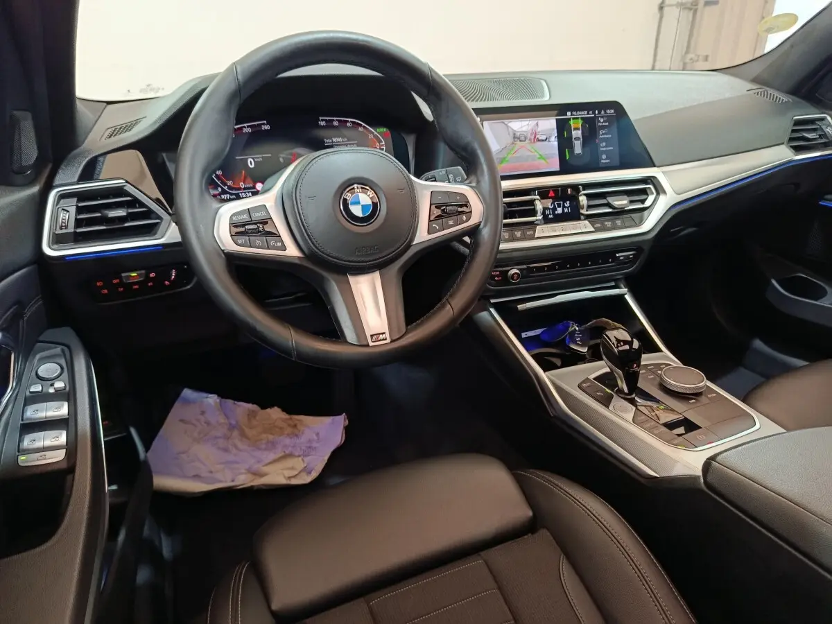 Vue intérieure avant de la BMW Série 3 318d 2022, tableau de bord noir avec écran tactile et volant cuir multifonctions.