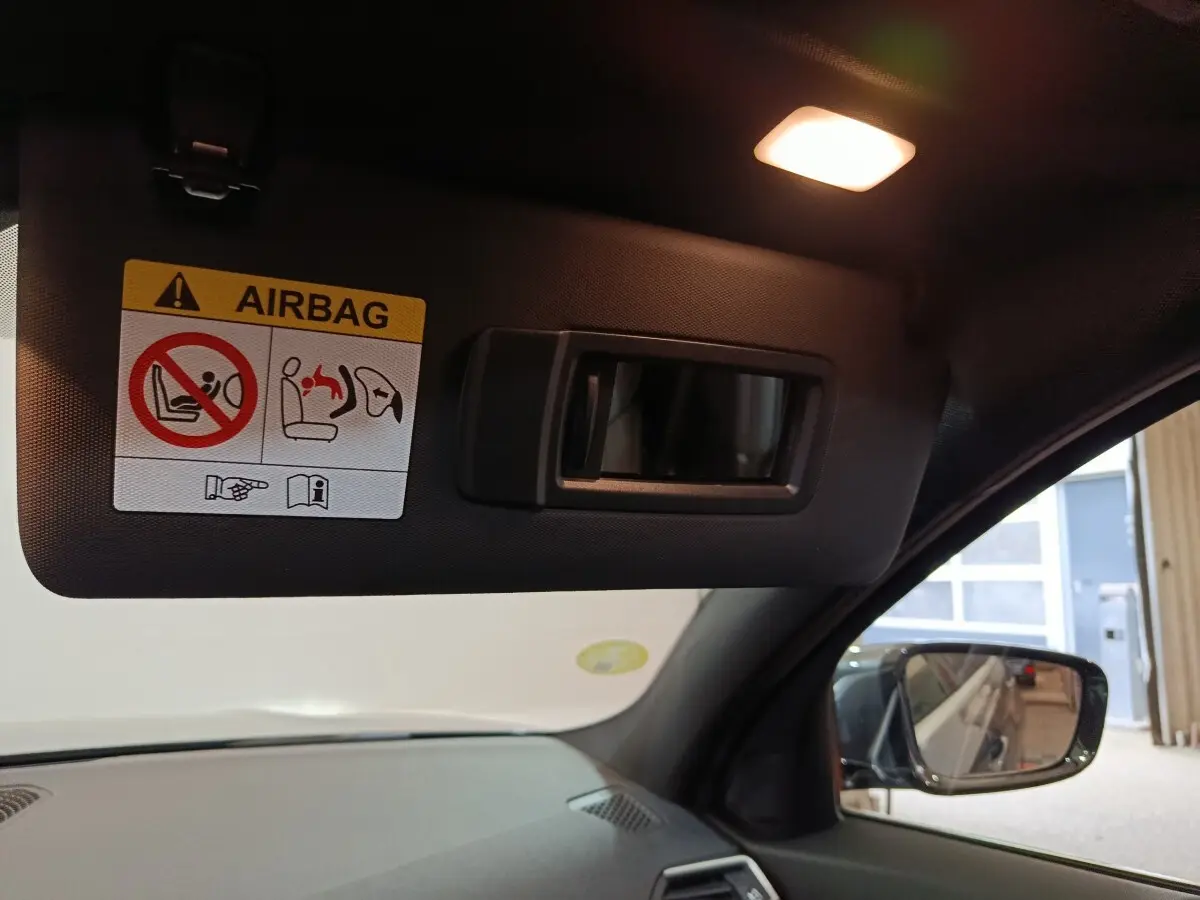 Détail du pare-soleil côté conducteur avec miroir intégré et avertissement airbag dans une BMW Série 3 grise.