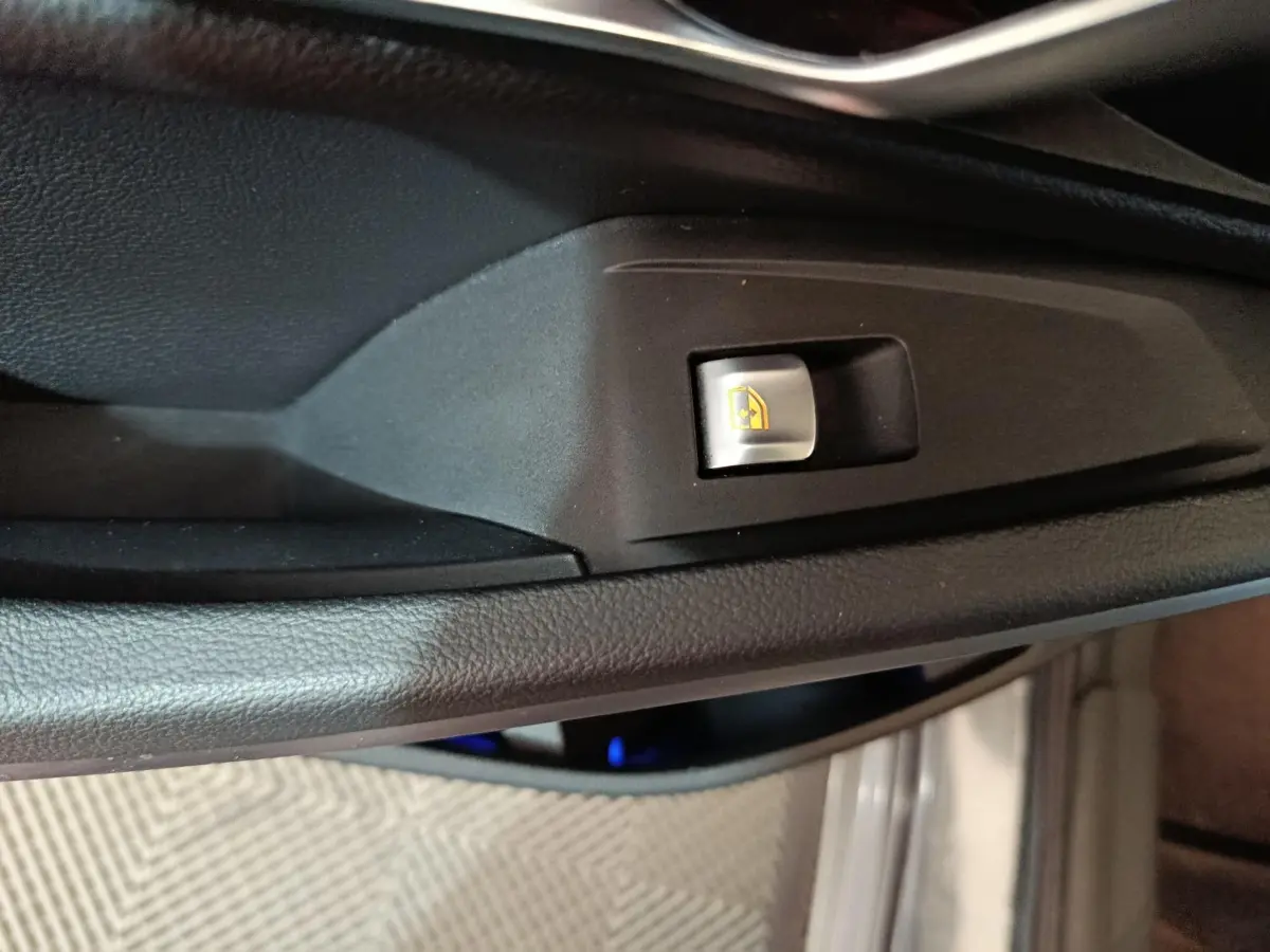 Gros plan sur le bouton de commande de lève-vitre côté conducteur dans l’habitacle noir d’une BMW Série 3 gris clair 2022.