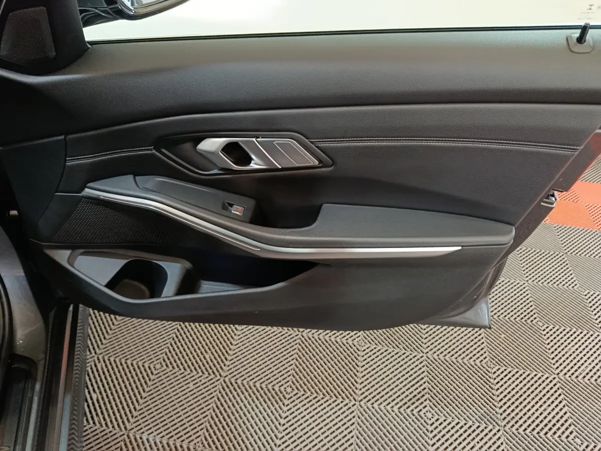 Vue intérieure du panneau de porte côté gauche gris foncé avec poignée argentée et insert décoratif sur BMW Série 3 318d 2022.
