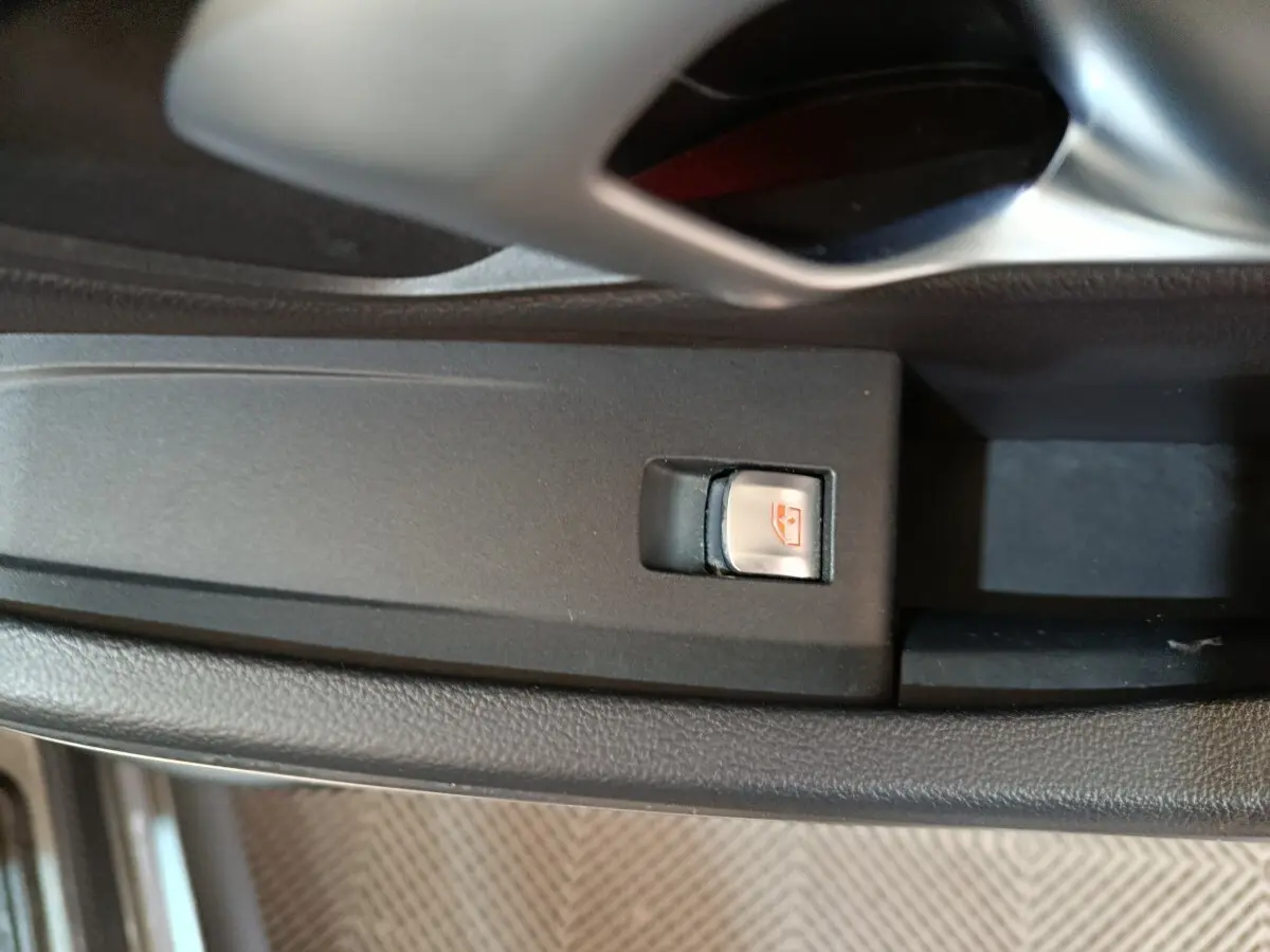 Gros plan sur le bouton de commande de lève-vitre côté conducteur dans une BMW Série 3 gris clair, intérieur noir.