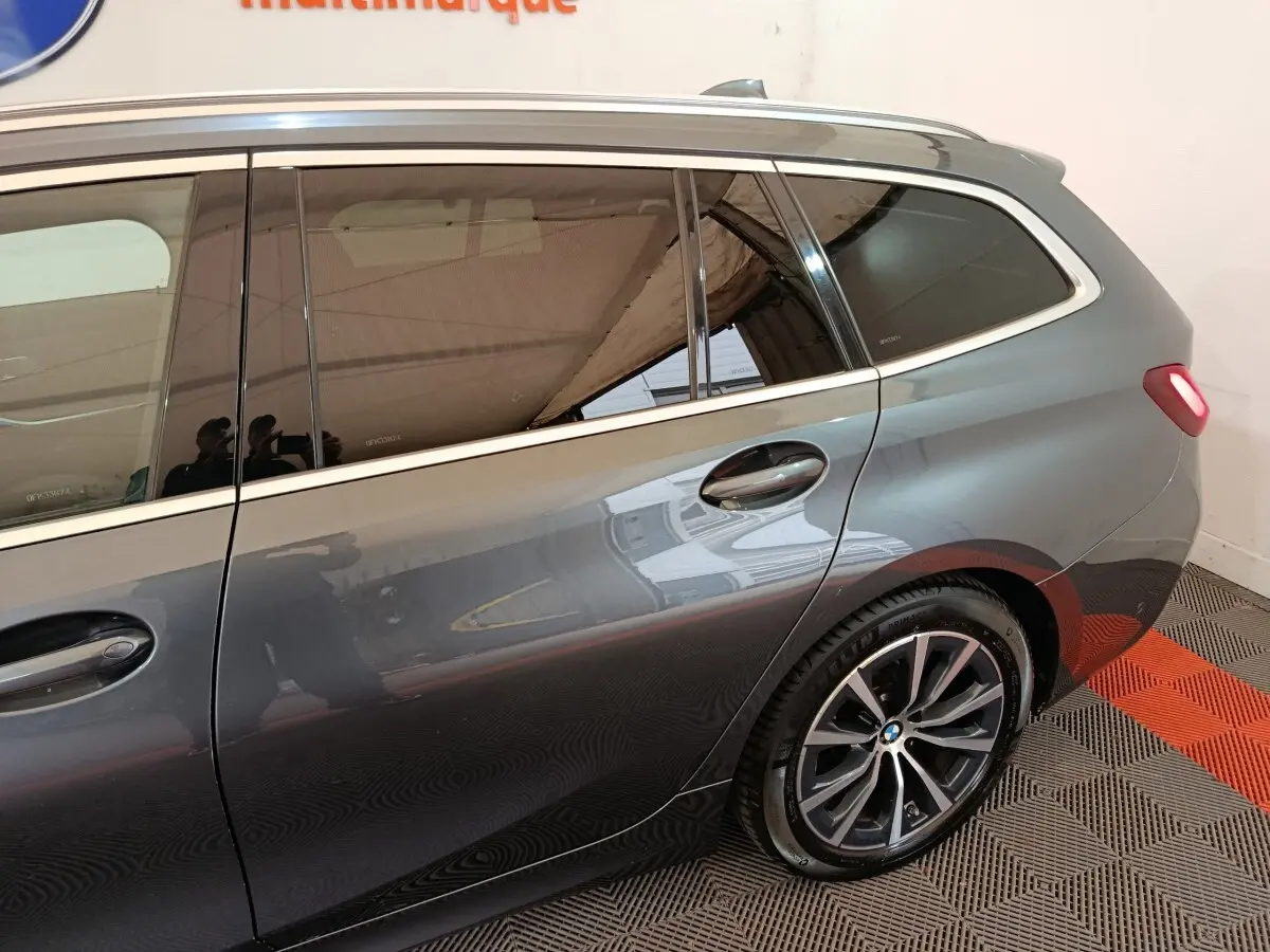 Vue latérale droite sur la partie arrière d'une BMW Série 3 Touring gris clair avec jante alliage et vitre teintée.