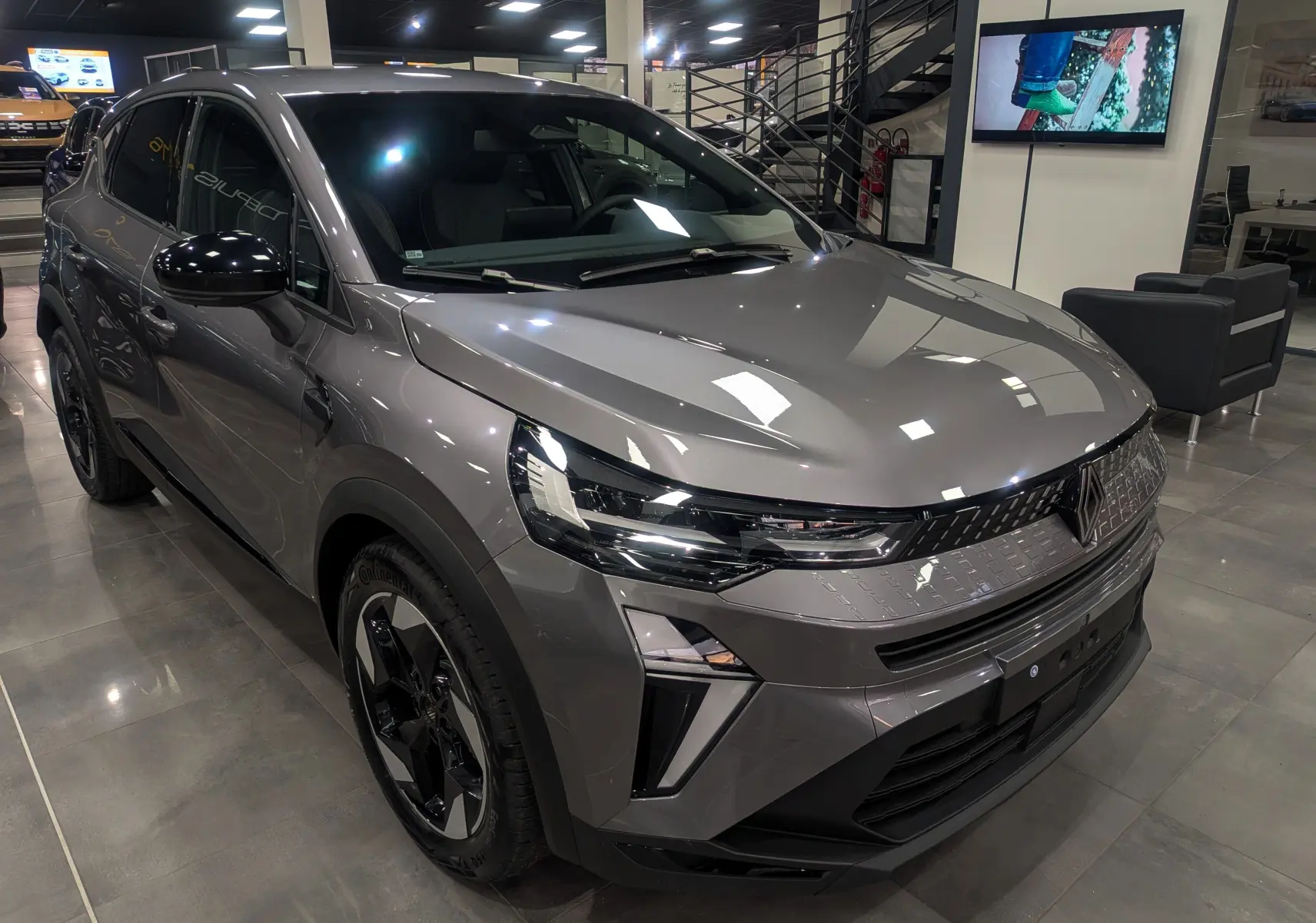 Renault Captur 2025 gris Cassiopé en 3/4 avant droit, avec calandre moderne et jantes noires bicolores.