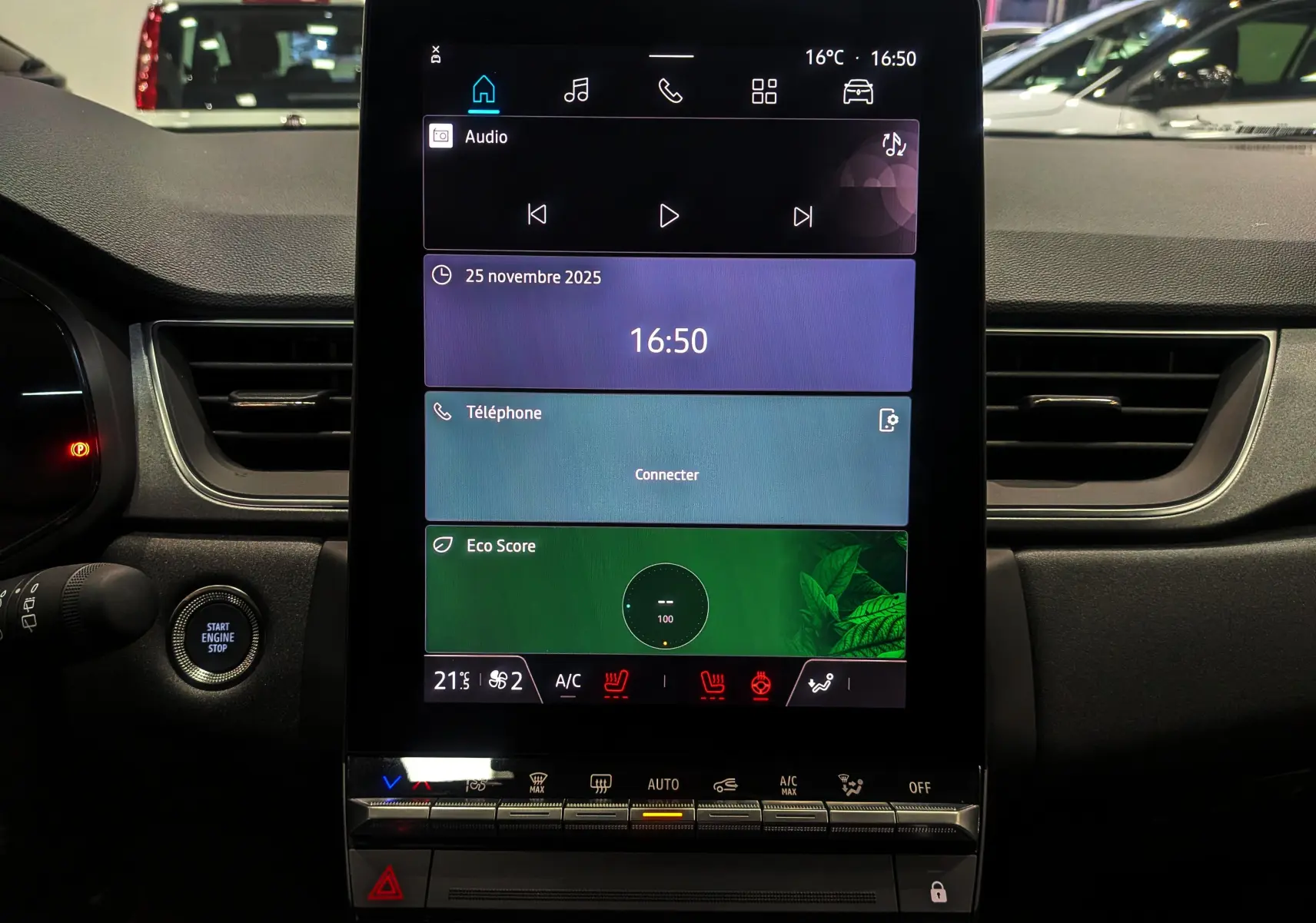 Écran tactile central allumé du tableau de bord du Renault Captur 2025, avec commandes de climatisation et bouton start visible.