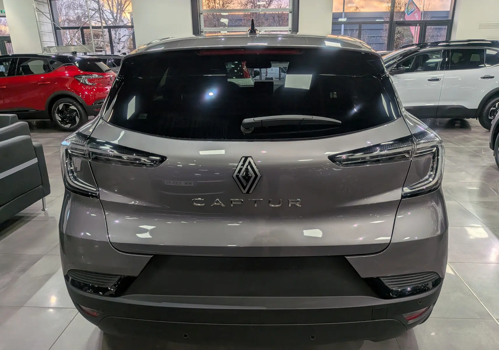 Vue arrière d'un Renault Captur gris Cassiopé 2025 avec feux LED et logo Renault bien visibles en showroom.