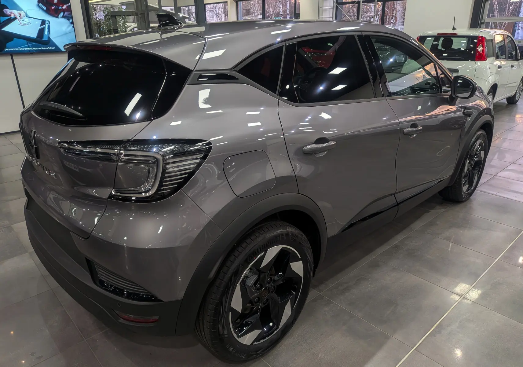 Vue 3/4 arrière droite du Renault Captur gris Cassiopé avec jantes noires bicolores et vitres teintées en showroom.