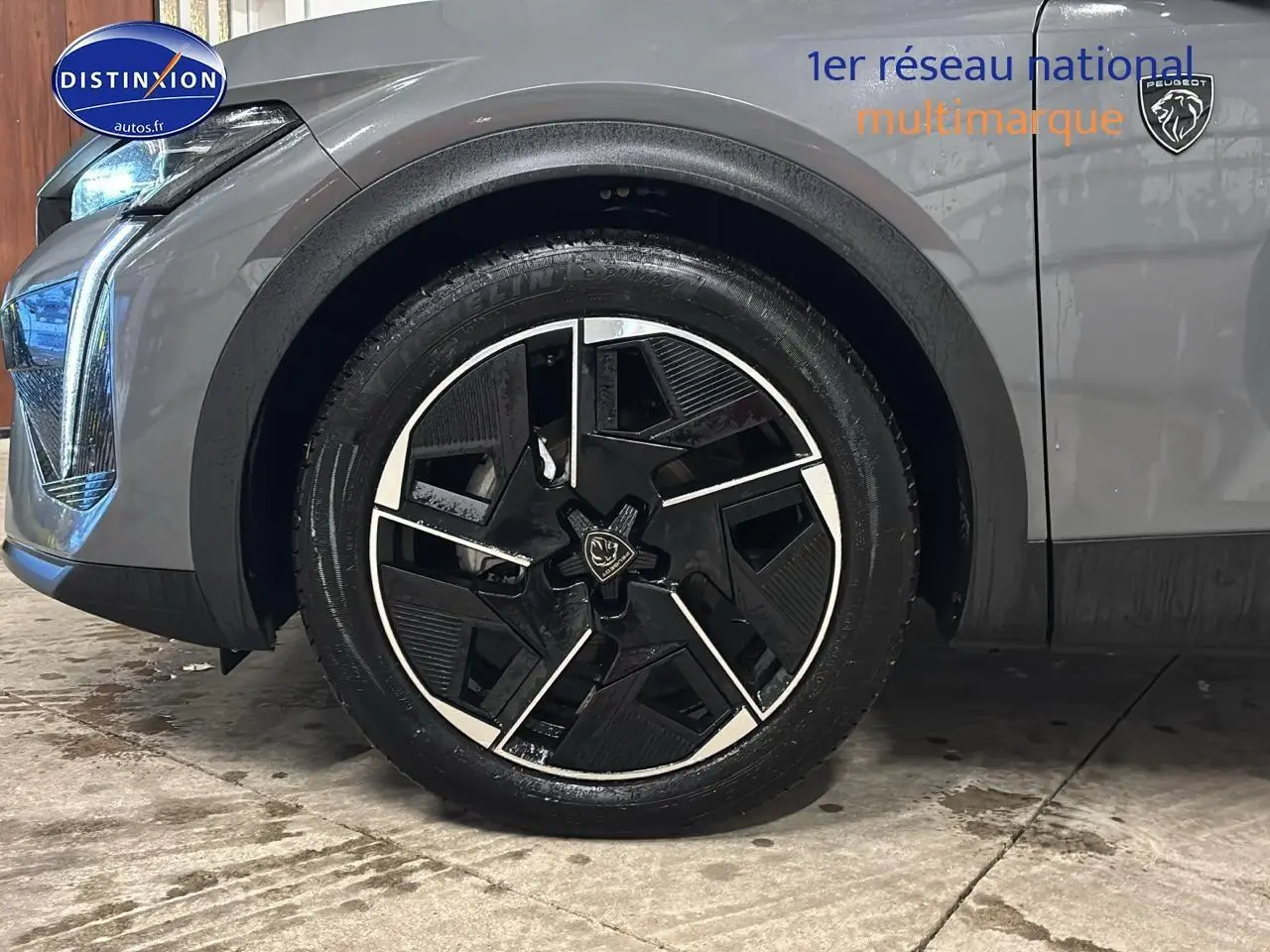 Gros plan sur la roue avant gauche et partie avant grise sélénite d'une Peugeot 408 Hybrid 145 GT e-dcs6 2025.