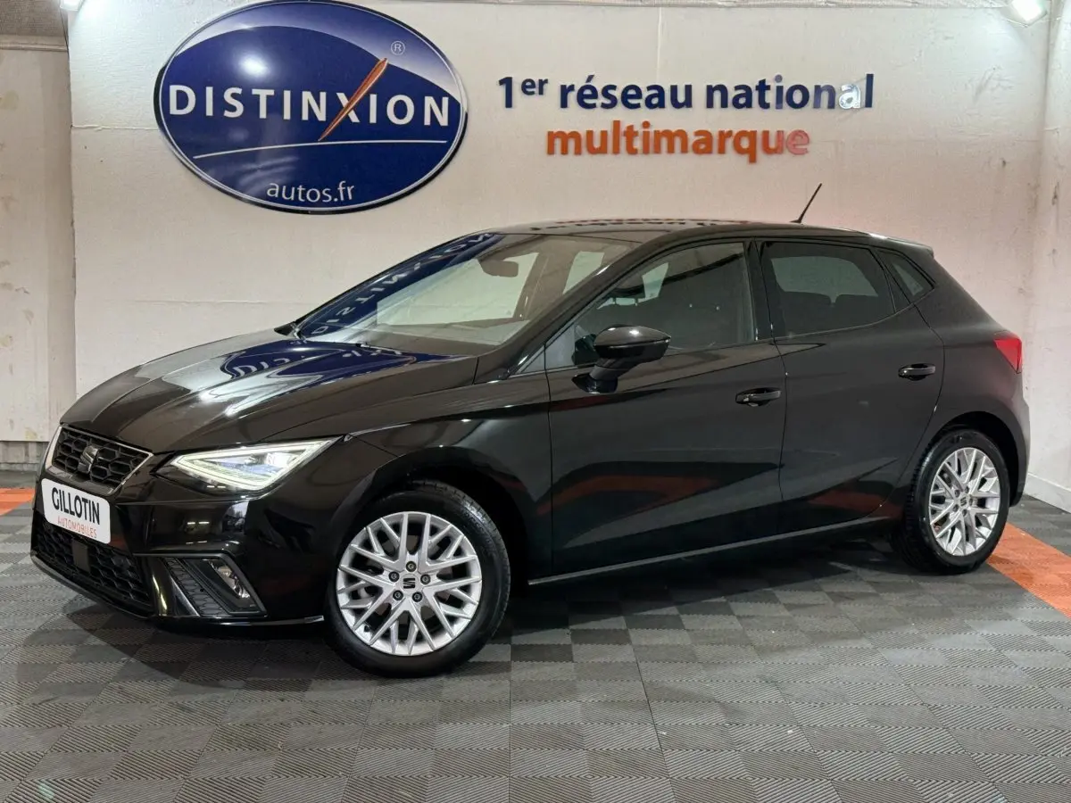 SEAT Ibiza 1.0 TSI 110 FR noire vue de profil côté gauche en intérieur avec jantes alliage et phares LED allumés.