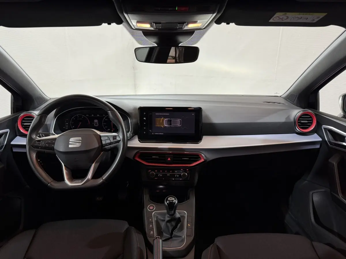 Vue frontale de l'habitacle noir de la SEAT Ibiza 1.0 TSI 110 FR 2024 avec volant cuir alu et écran tactile central.