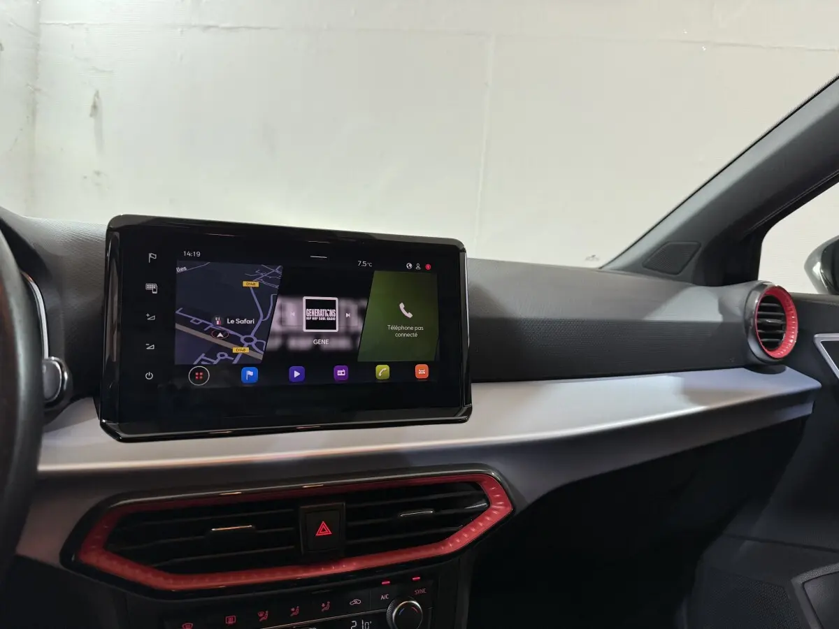 Vue intérieure du tableau de bord de la SEAT Ibiza 2024 noir, avec écran tactile central et aérateurs rouges.