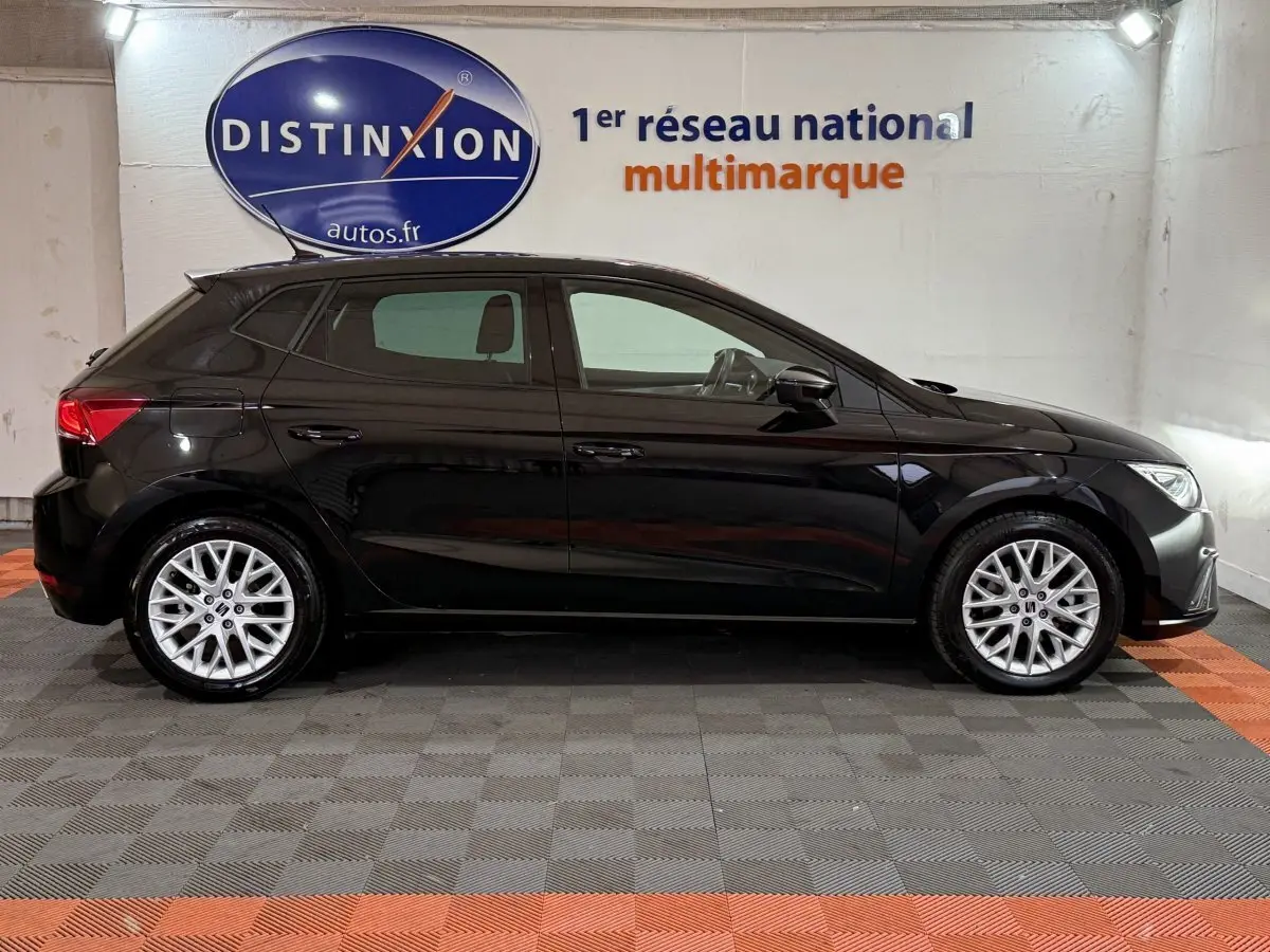 Profil côté gauche d'une SEAT Ibiza 1.0 TSI 110 FR noire, avec jantes alliage et intérieur visible en arrière-plan.