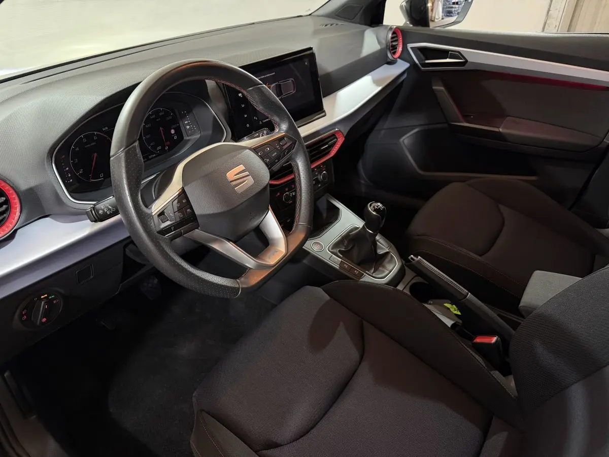 Vue intérieure côté conducteur de la SEAT Ibiza 1.0 TSI 110 FR 2024, volant cuir alu et écran tactile central.