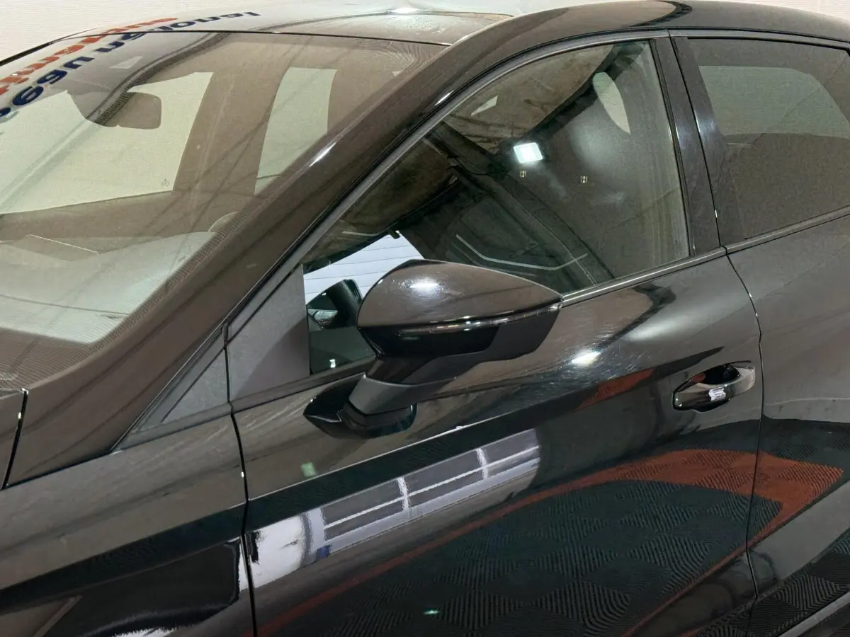 Vue rapprochée du côté gauche d’une SEAT Ibiza 1.0 TSI 110 FR noire, mettant en valeur le rétroviseur et la poignée de porte.