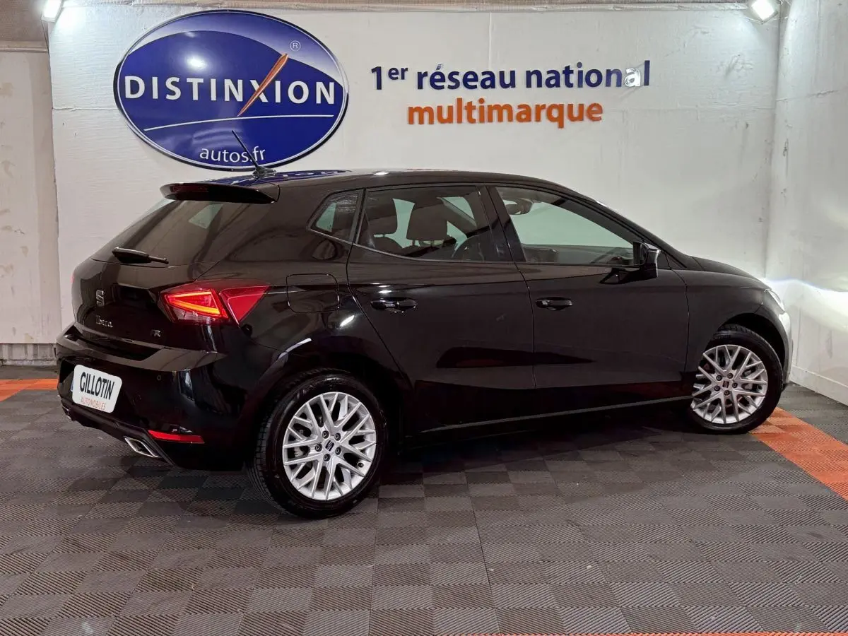 Vue côté droit arrière d'une SEAT Ibiza 1.0 TSI 110 FR noire avec jantes alliage et feux LED distinctifs.