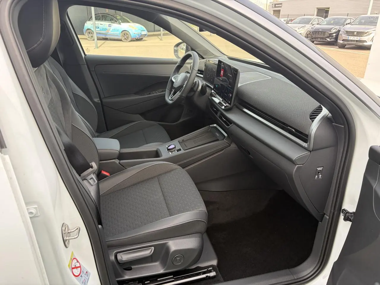 Intérieur avant droit du Volkswagen T-Roc blanc pur, avec tableau de bord moderne et sièges tissu R-Line noirs.