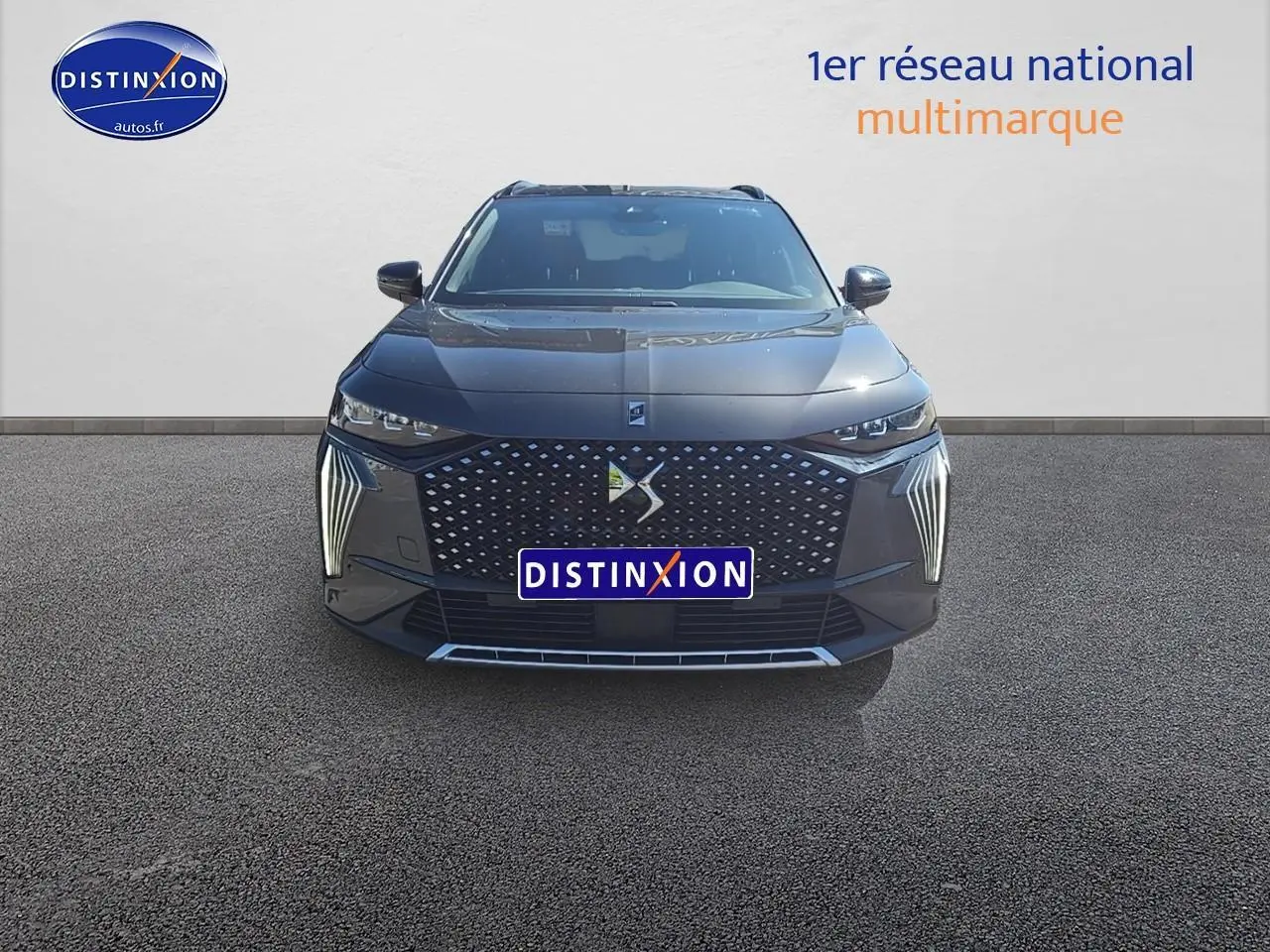 Vue frontale d'un DS7 gris titane 2025 avec calandre DS Pixel LED et feux verticaux distinctifs allumés.