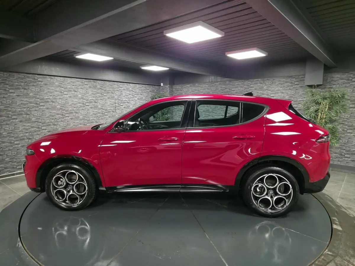 Vue de profil côté gauche d'un Alfa Romeo Tonale rouge avec jantes en alliage et détails noirs brillants.