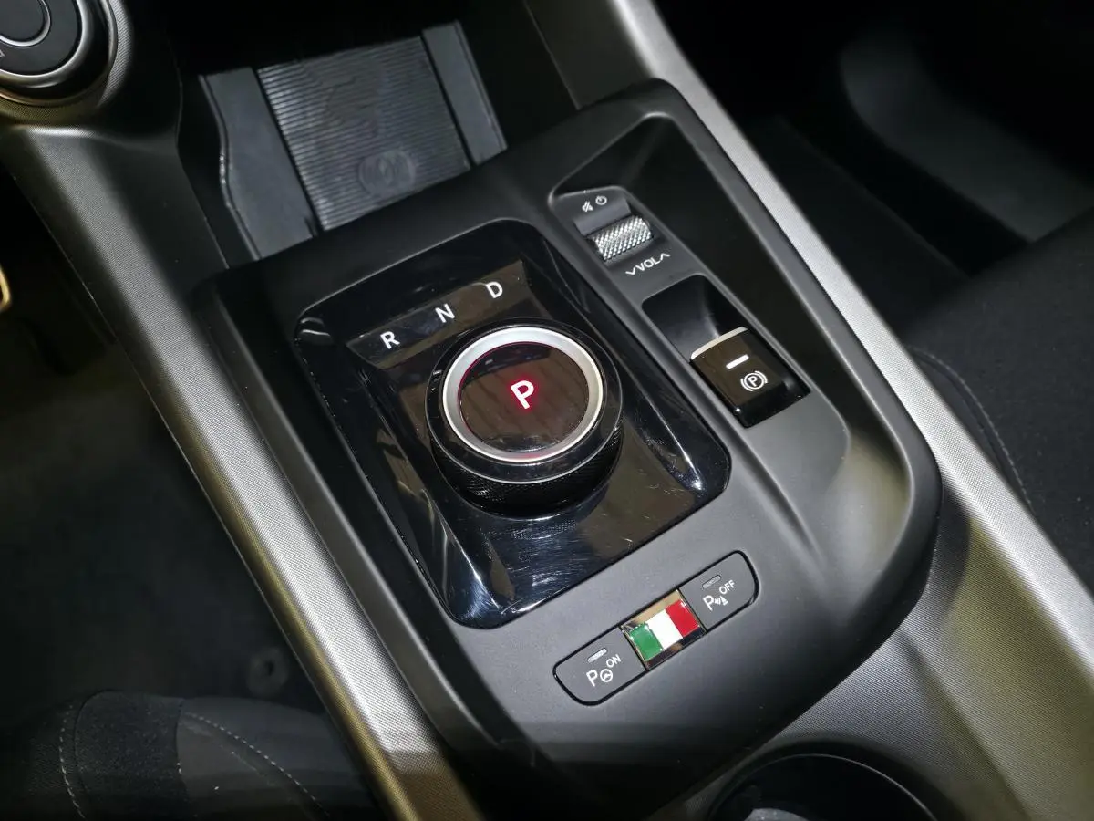Gros plan sur la console centrale noire de l'Alfa Romeo Tonale avec sélecteur rotatif de vitesse et commande de volume.