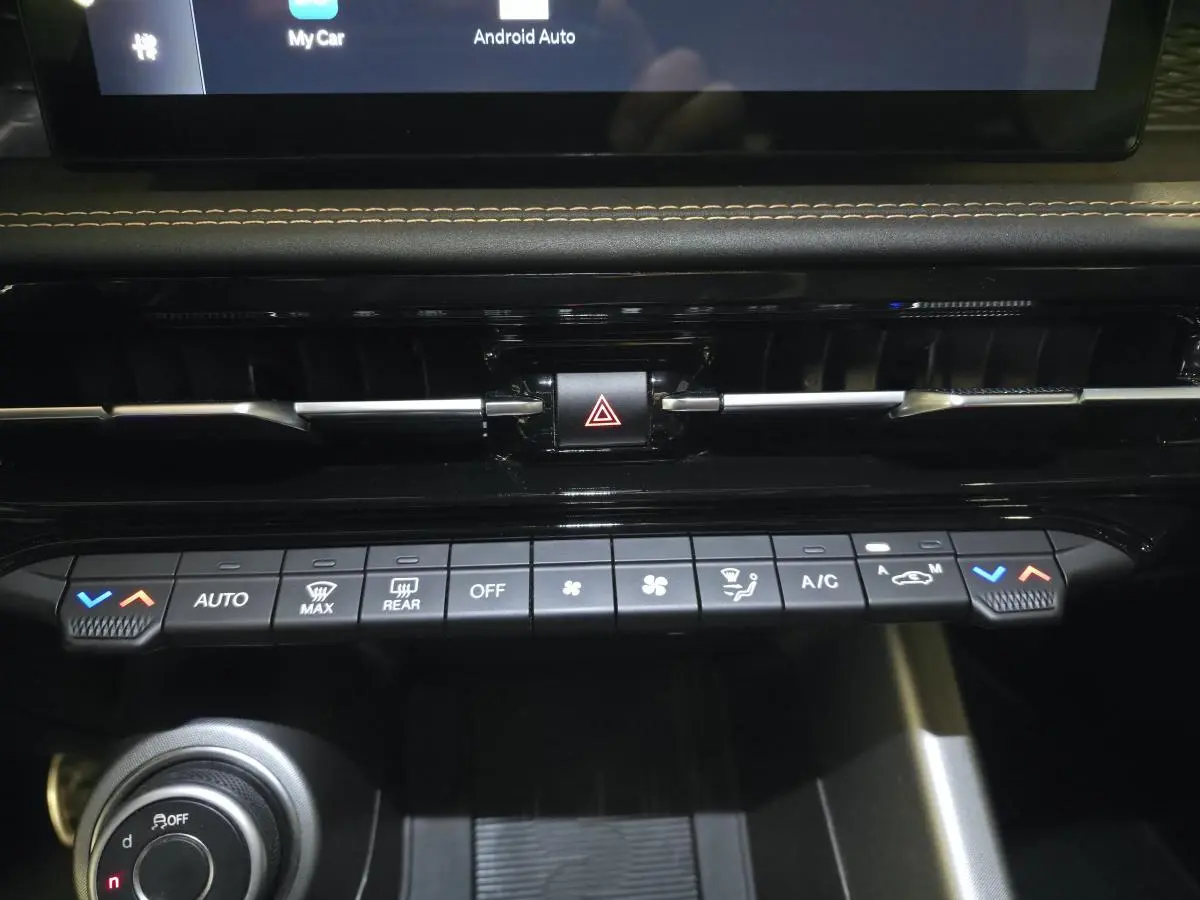 Vue rapprochée de la console centrale noire de l'Alfa Romeo Tonale 2025 avec commandes climatisation et bouton hazard.