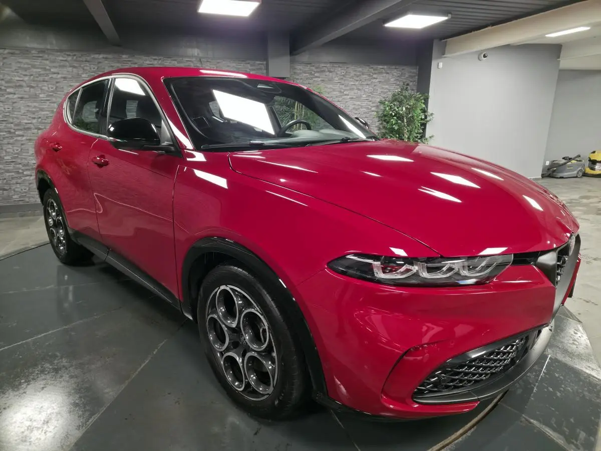 Alfa Romeo Tonale rouge vue 3/4 avant droit, avec jantes alliage 18 pouces et calandre caractéristique Scudetto noire.