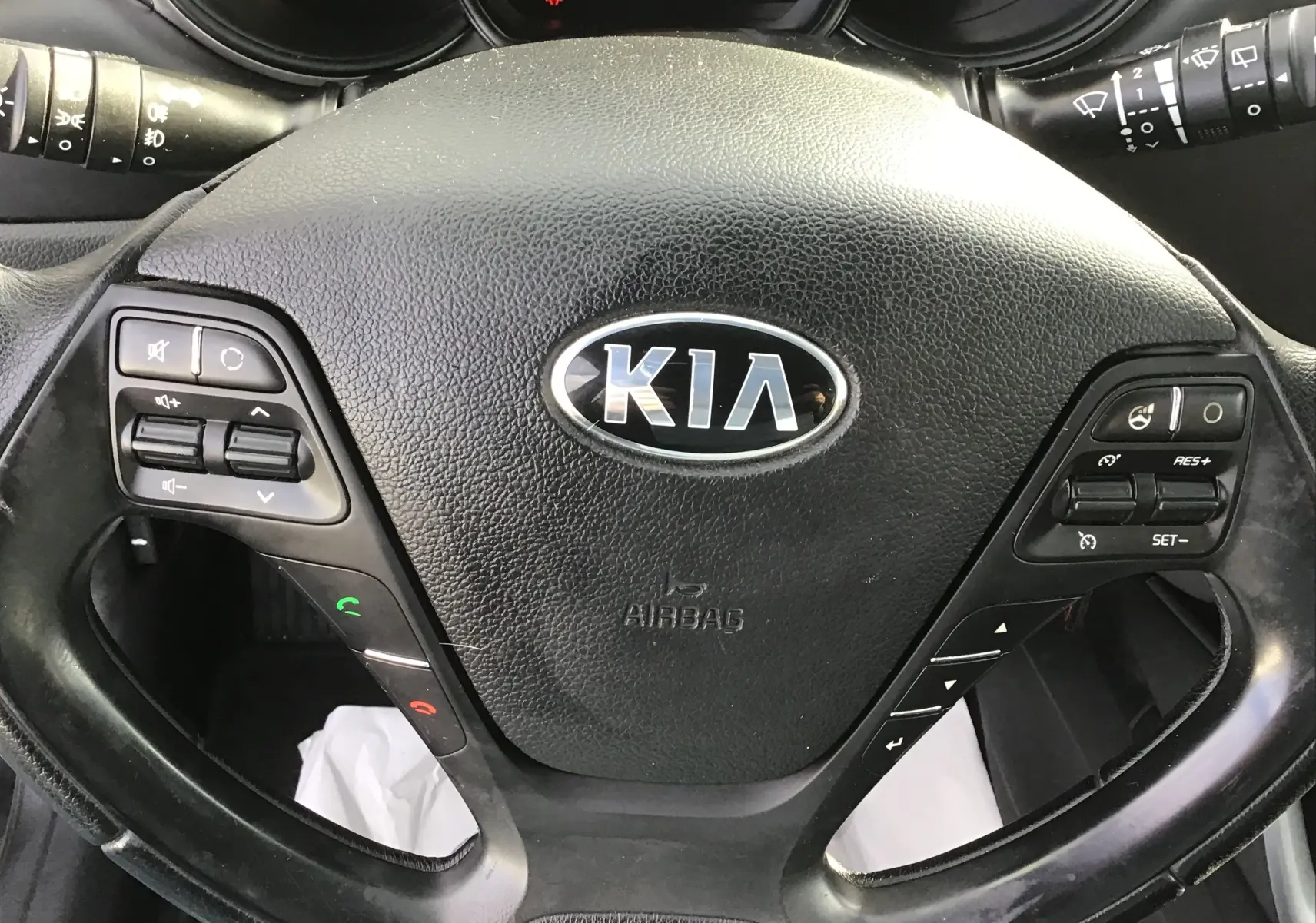 Gros plan sur le volant noir de la Kia CEE'D SW 2017, avec commandes audio et régulateur de vitesse intégrés.