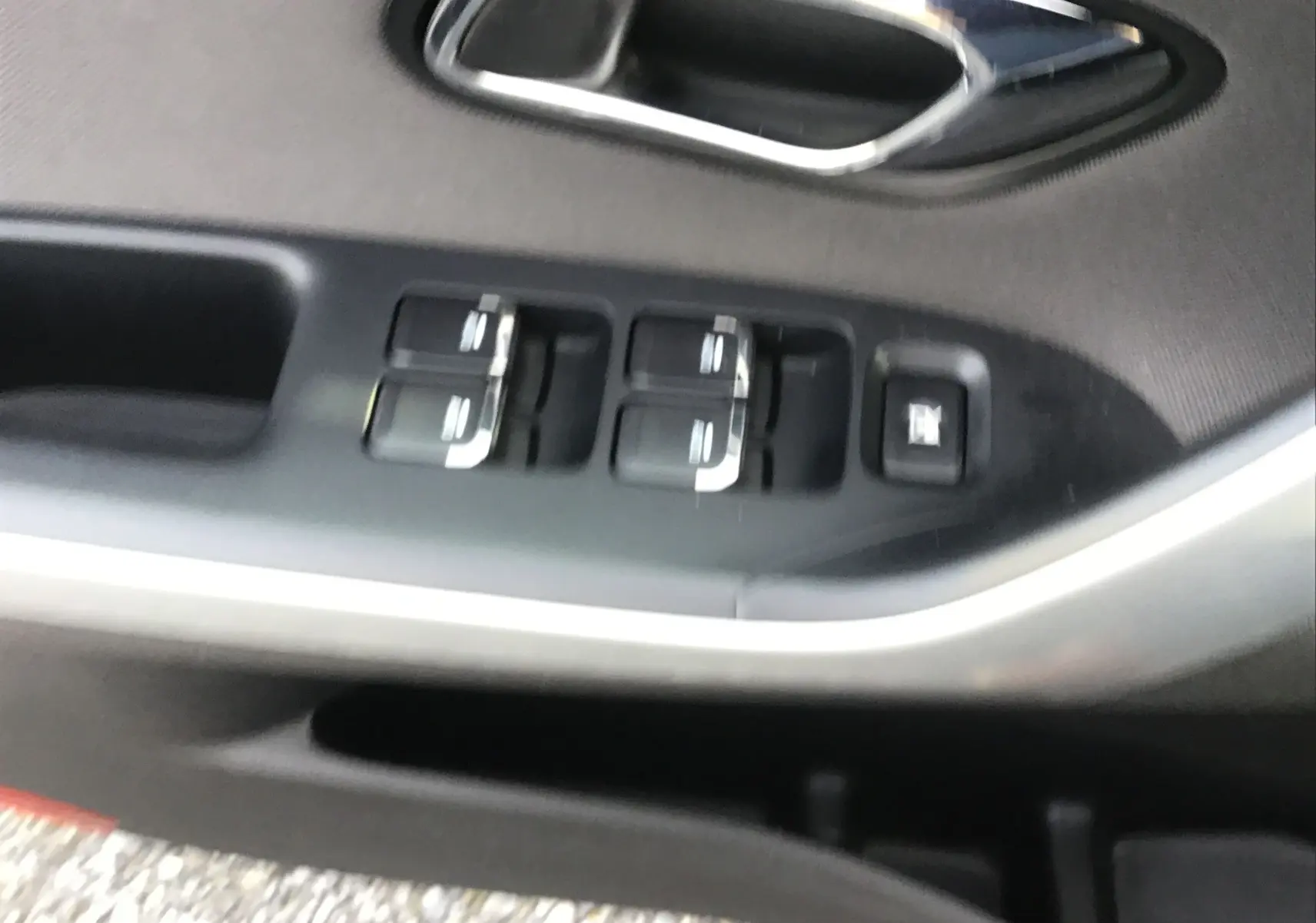 Gros plan sur la commande des vitres électriques côté conducteur d'une KIA CEE'D SW noire, avec poignée de porte chromée.