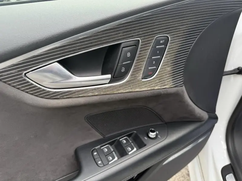 Gros plan sur la porte avant gauche blanche d'une Audi A7 Sportback 2018, avec commandes de vitres et insert décoratif en aluminium brossé.