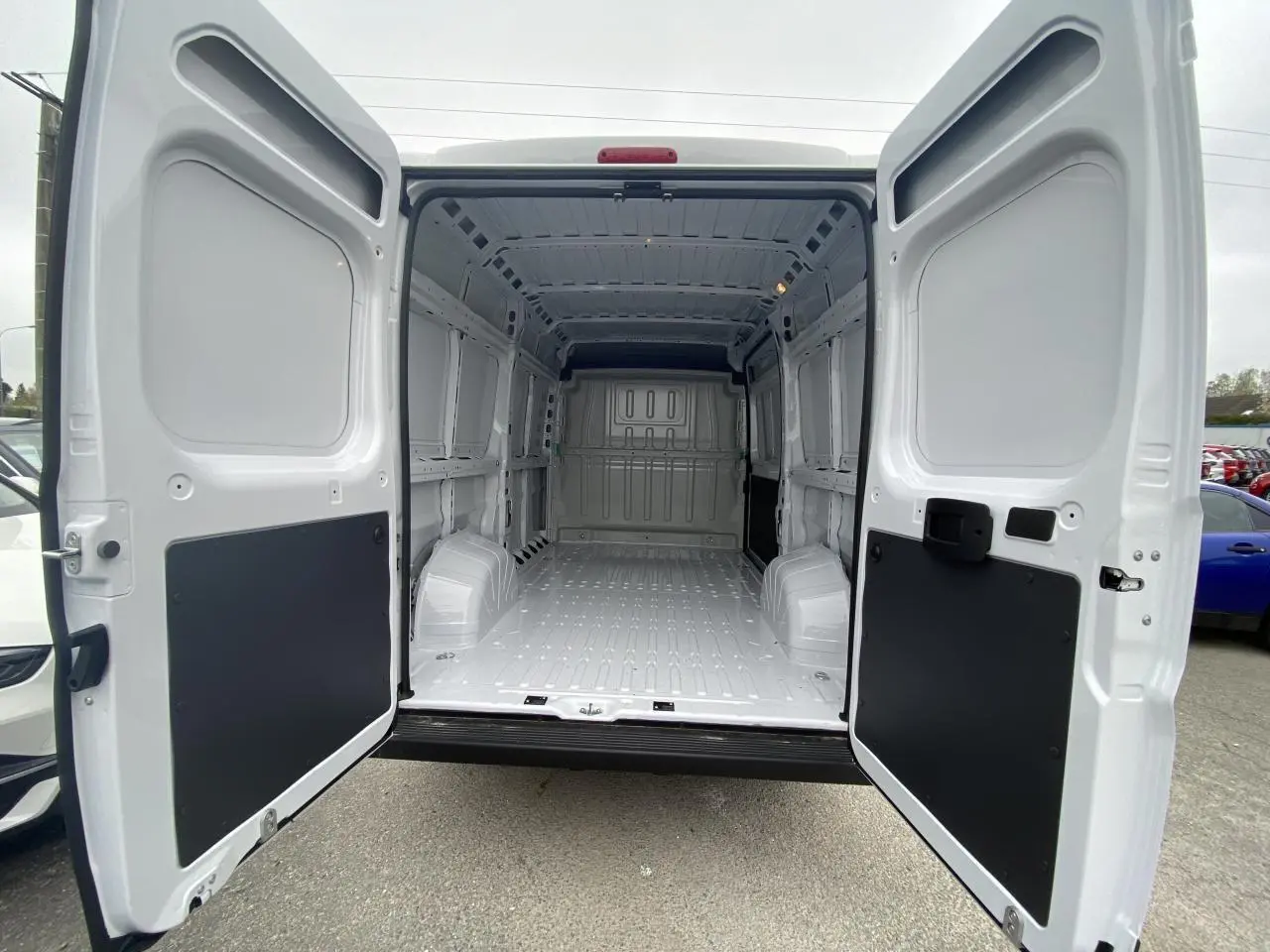 Vue arrière du fourgon blanc Opel Movano 2022 avec portes ouvertes dévoilant l'intérieur spacieux et tôlé.