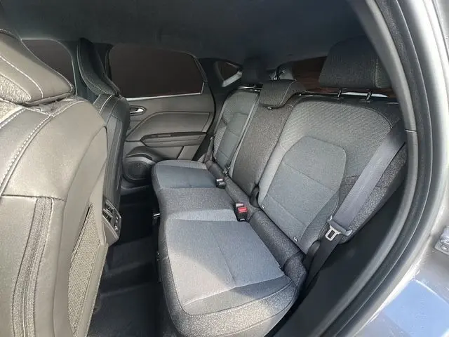 Vue intérieure arrière droite du Renault Captur 2025, sièges tissu gris avec ceintures de sécurité visibles.