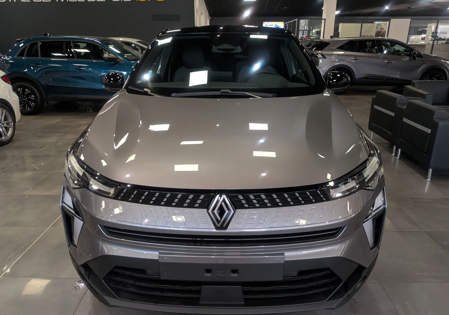 Vue frontale d'un Renault Captur 2025 gris Cassiopé avec toit noir, éclairage LED et calandre moderne en showroom.