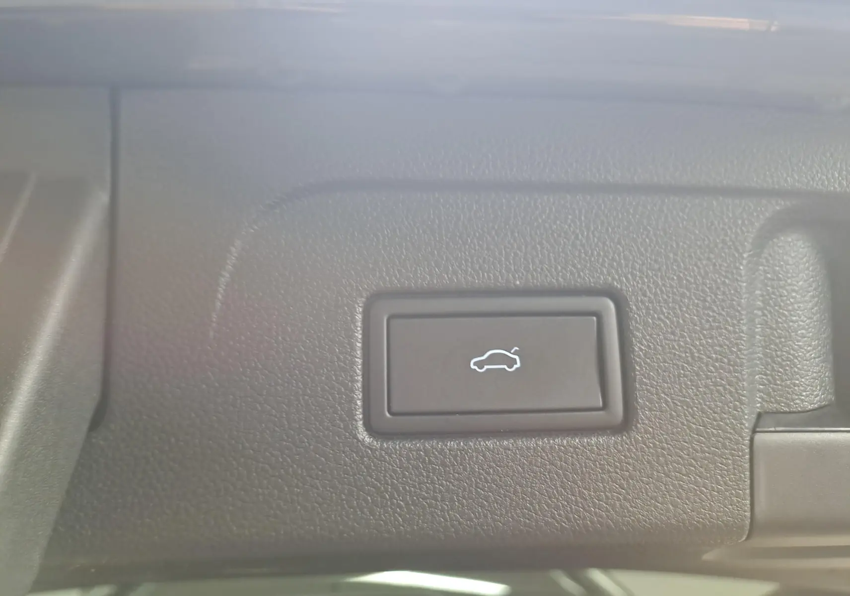 Bouton d'ouverture électrique du hayon sur tableau de bord intérieur du Volkswagen Touran gris Dauphin 2024.