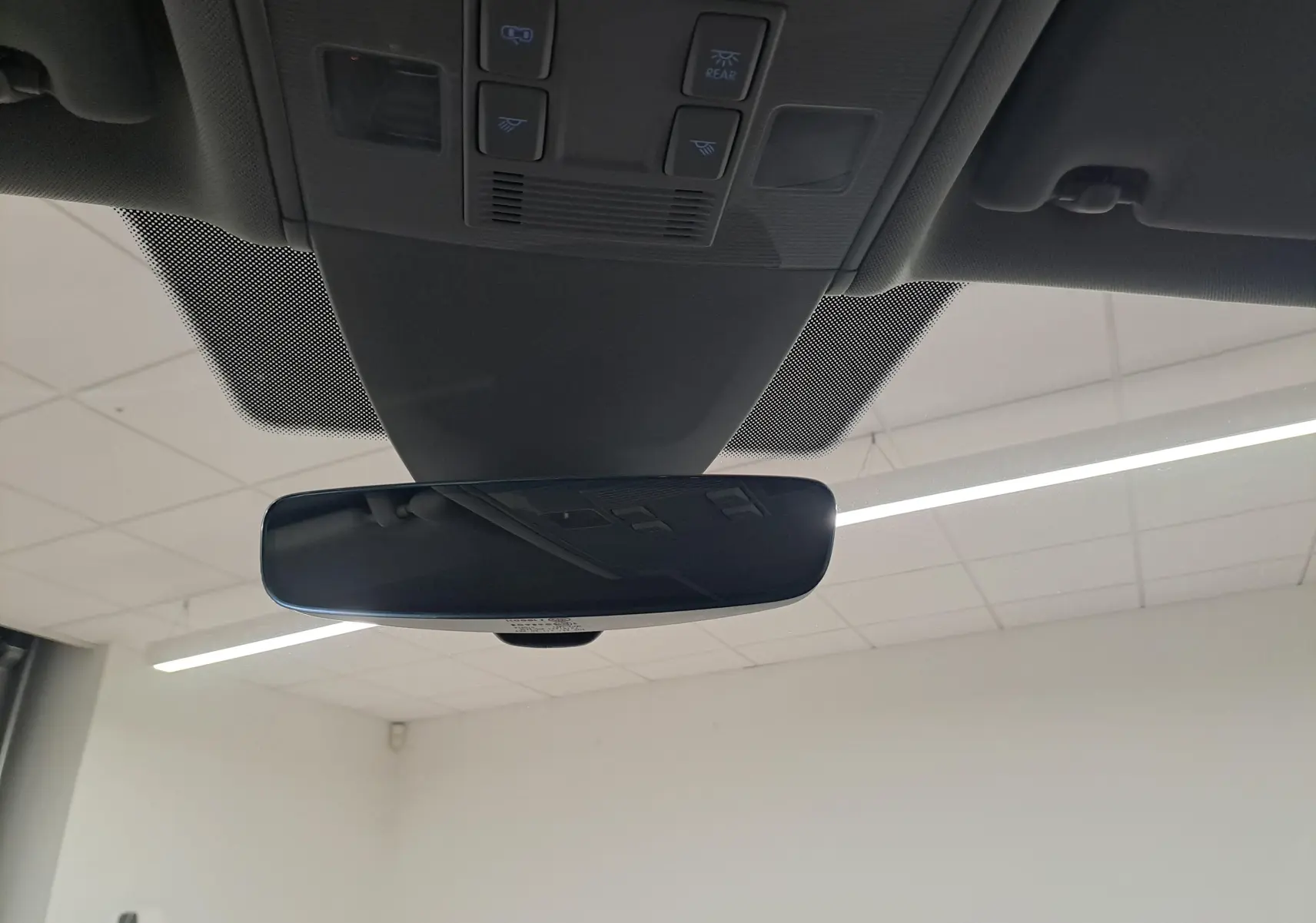 Vue en gros plan du rétroviseur intérieur et de la console de toit d’un Volkswagen Touran 2024 gris Dauphin.