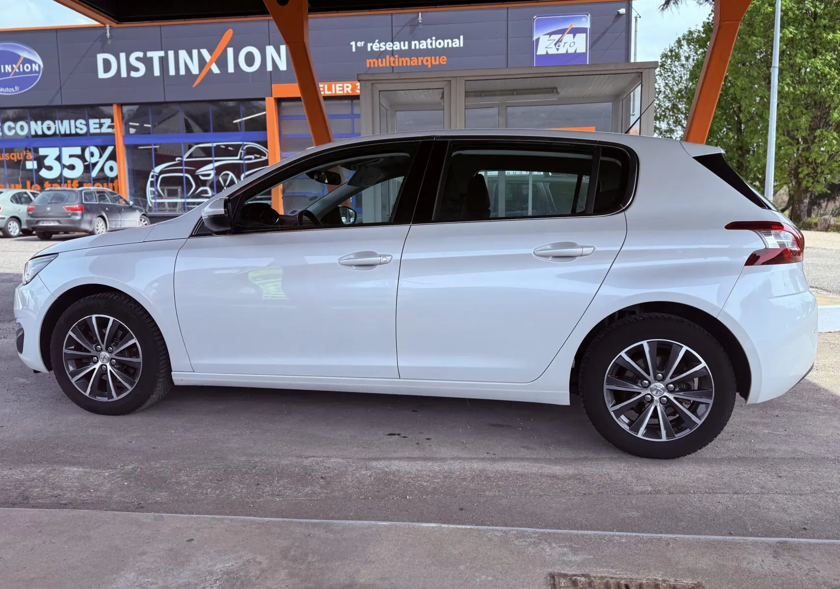 Profil latéral droit d'une Peugeot 308 blanche nacrée 5 portes, avec jantes alliage et vitres teintées.