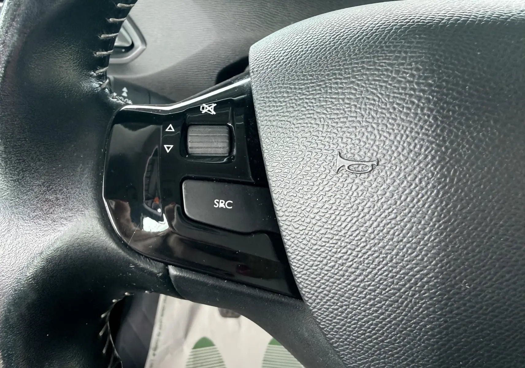 Gros plan sur les commandes noires du volant côté gauche de la Peugeot 308 blanche de 2016.