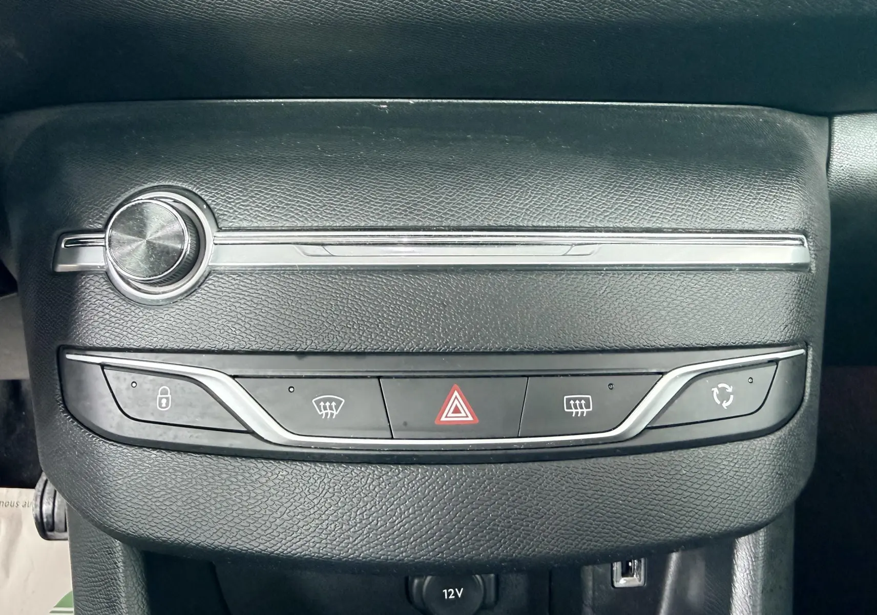 Gros plan sur la console centrale noire de la Peugeot 308 avec boutons de verrouillage, dégivrage et alerte.