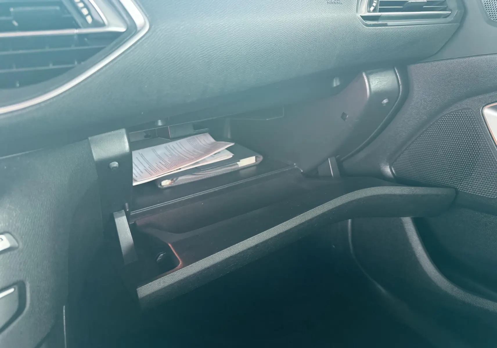 Vue intérieure côté passager du coffre à gants ouvert de la Peugeot 308, avec documents visibles à l'intérieur.