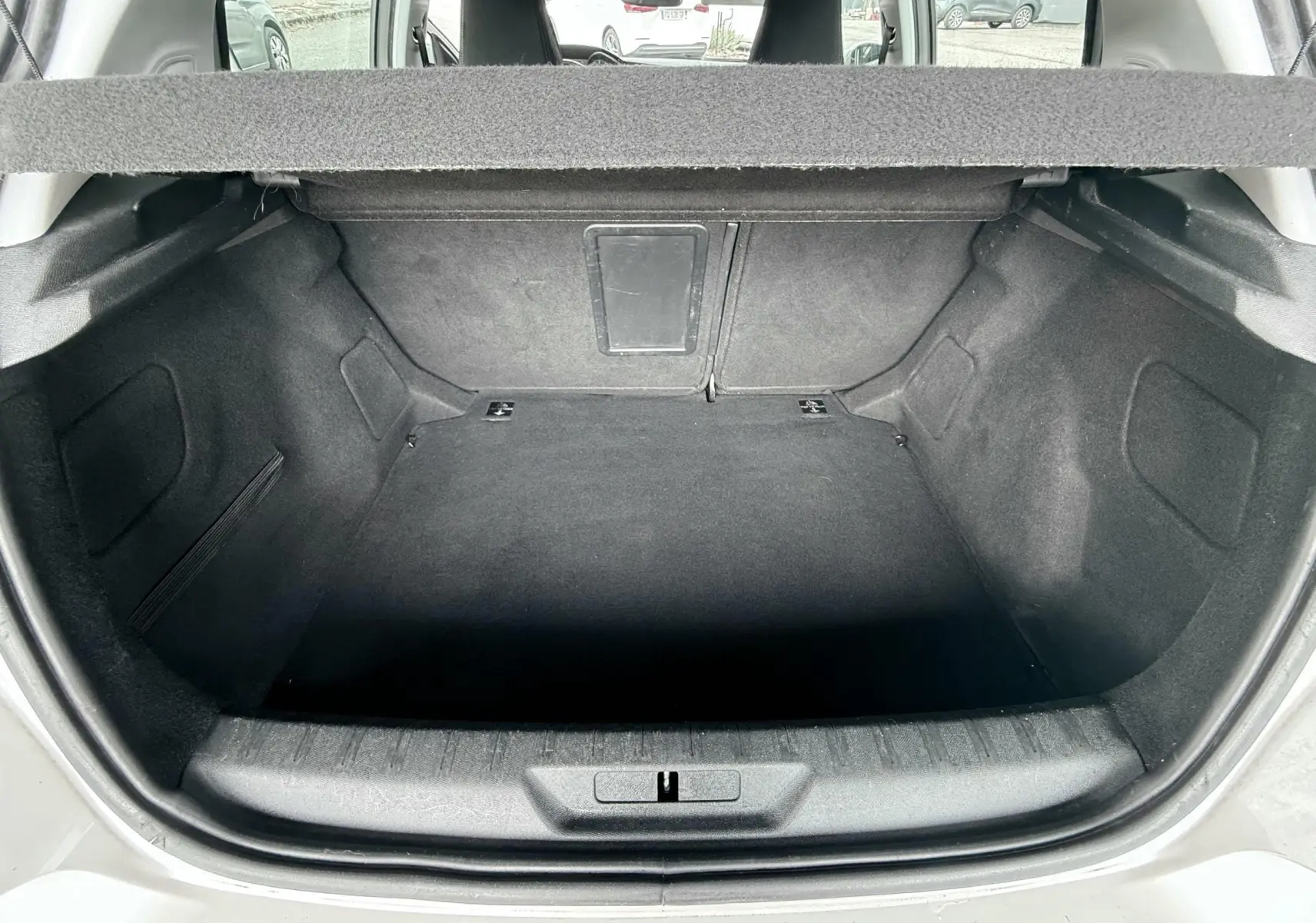 Coffre ouvert vu de l'arrière d'une Peugeot 308 blanche, montrant un espace de chargement vide et propre.