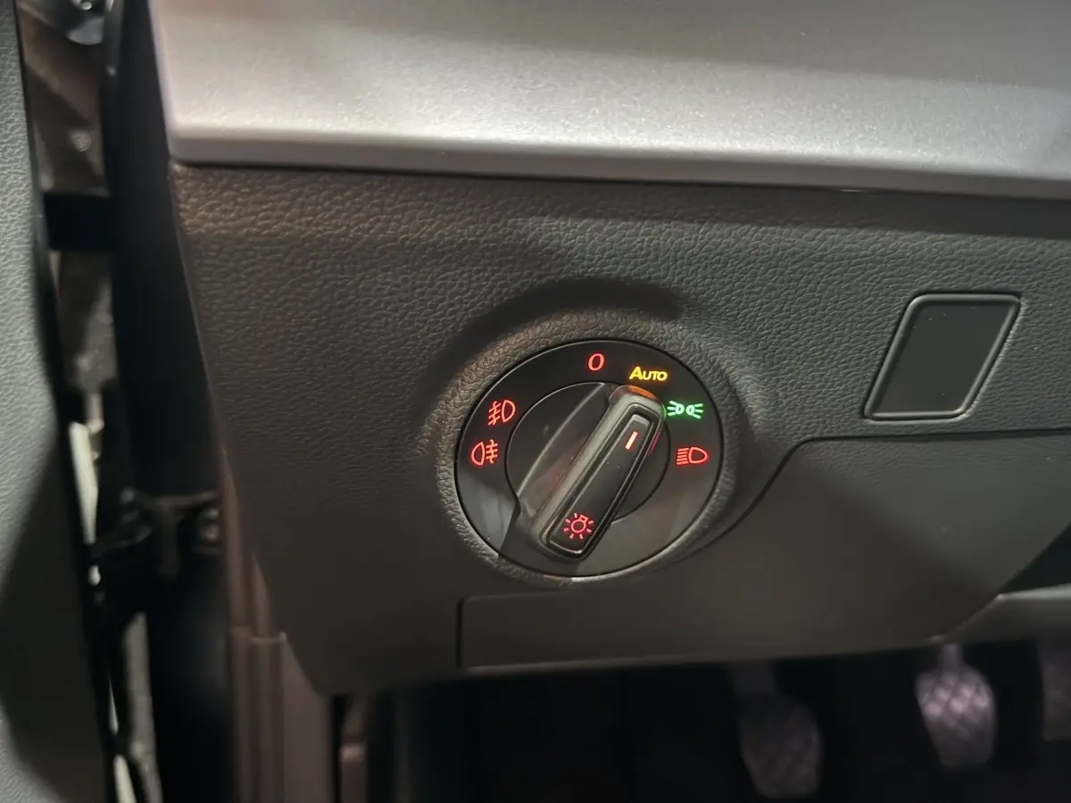 Gros plan sur le bouton de commande des phares avec réglage automatique, dans l’habitacle gris foncé de la SEAT Ibiza 2024.
