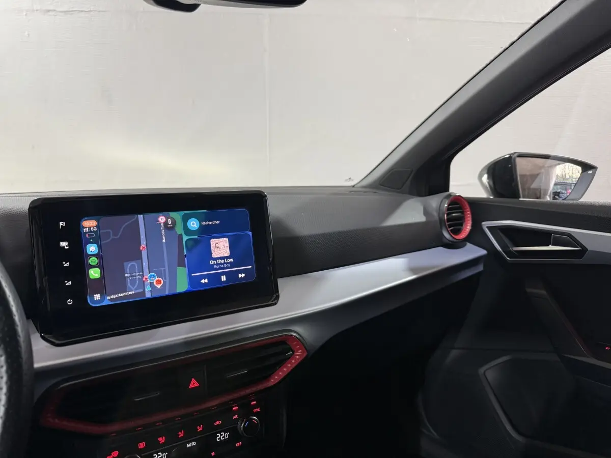 Vue intérieure côté passager de la SEAT Ibiza gris foncé 2024, avec écran tactile central et aérateurs rouges.