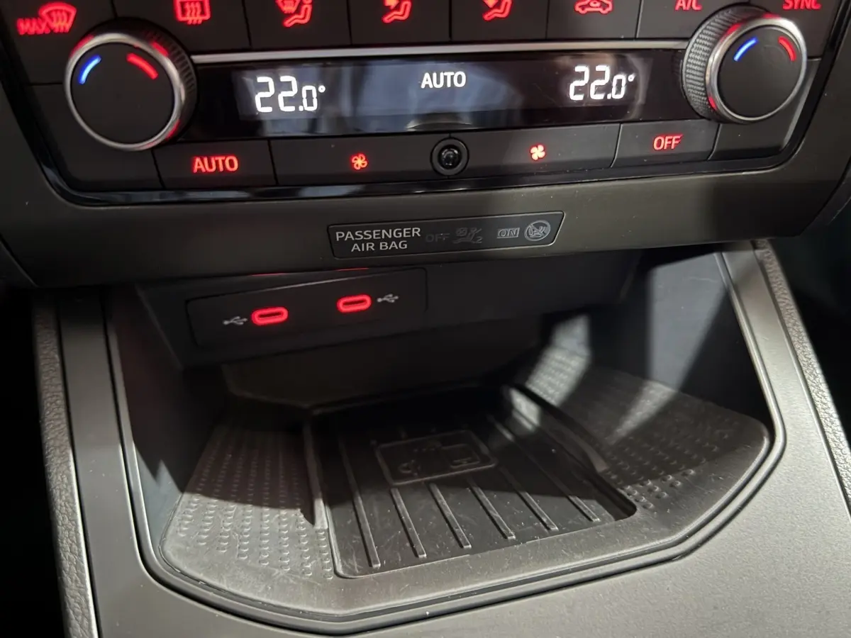 Gros plan sur la console centrale de la SEAT Ibiza 2024 gris foncé, montrant la climatisation digitale et deux ports USB rouges.