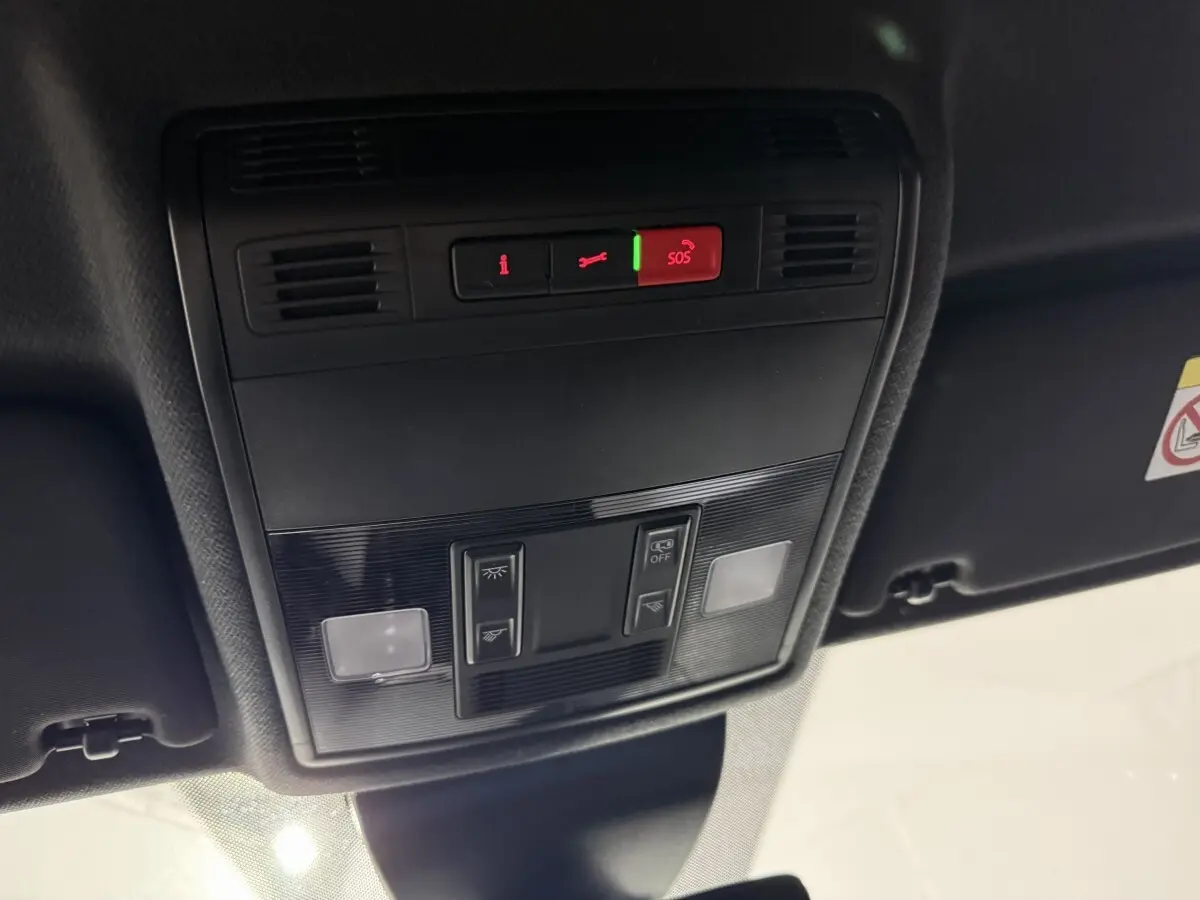 Vue en contre-plongée du panneau de commandes au plafond intérieur de la SEAT IBIZA gris foncé, avec bouton SOS éclairé en rouge.