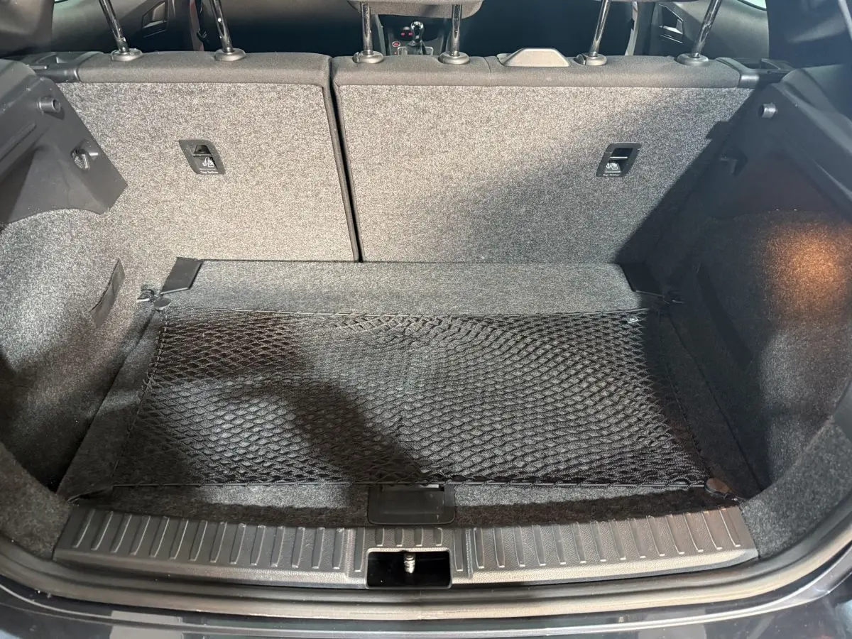 Vue du coffre ouvert de la SEAT Ibiza 1.0 TSI 110 FR gris foncé, montrant la banquette arrière et un filet de rangement.