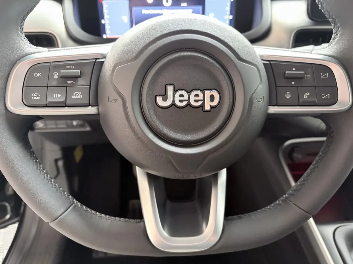 Gros plan sur le volant cuir noir du Jeep Avenger 2025 avec commandes multifonctions et logo central Jeep.