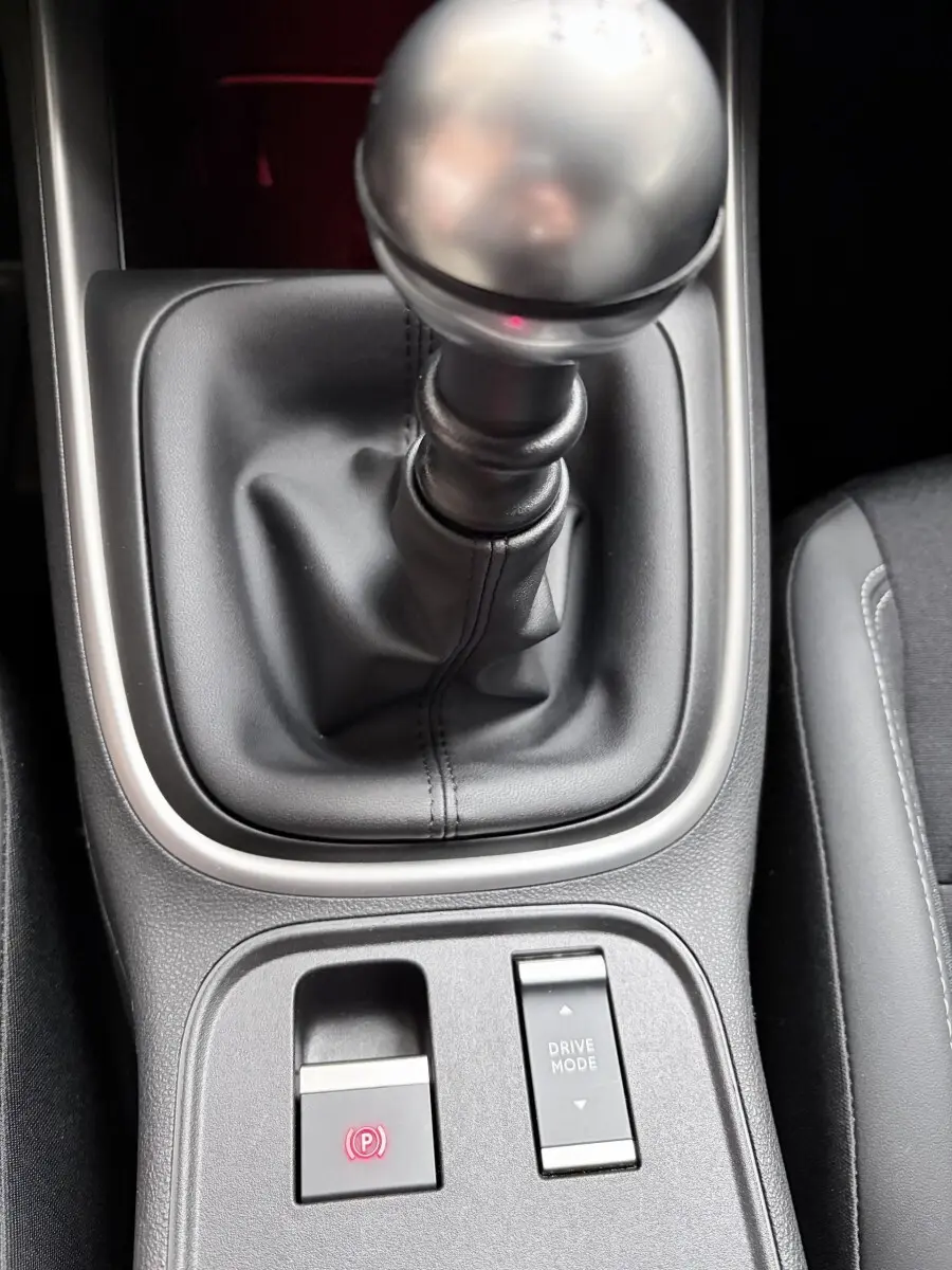Gros plan sur la commande de boîte manuelle et les boutons de frein à main électrique et mode de conduite dans un Jeep Avenger noir.