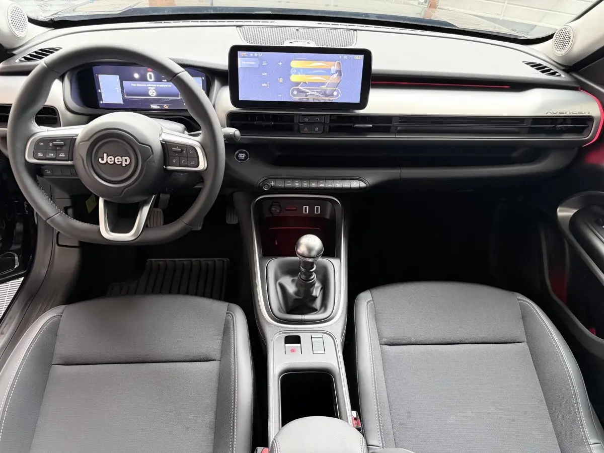 Intérieur Jeep Avenger 2025 vu de face, volant cuir, écran tactile central 10,25 pouces et levier de vitesse manuel.
