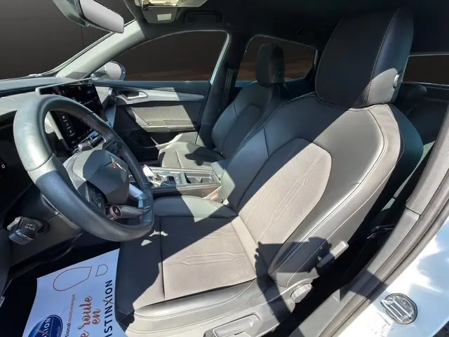 Vue intérieure côté conducteur du CUPRA Formentor blanc 2025, sièges en cuir noir avec coutures contrastées et volant multifonctions.