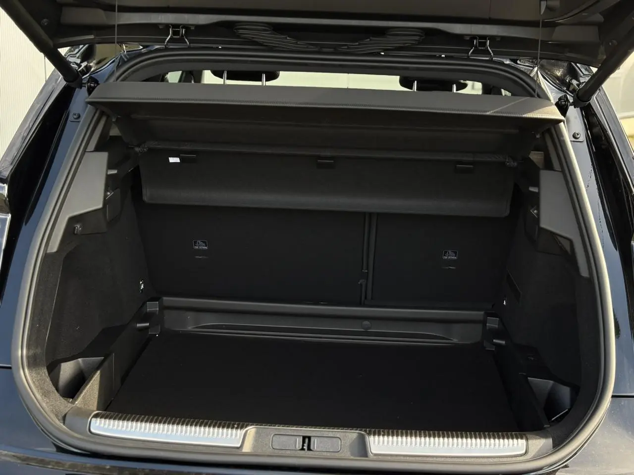 Coffre ouvert vu de l'arrière d'un DS7 noir Perla, montrant un espace de chargement propre et bien fini.