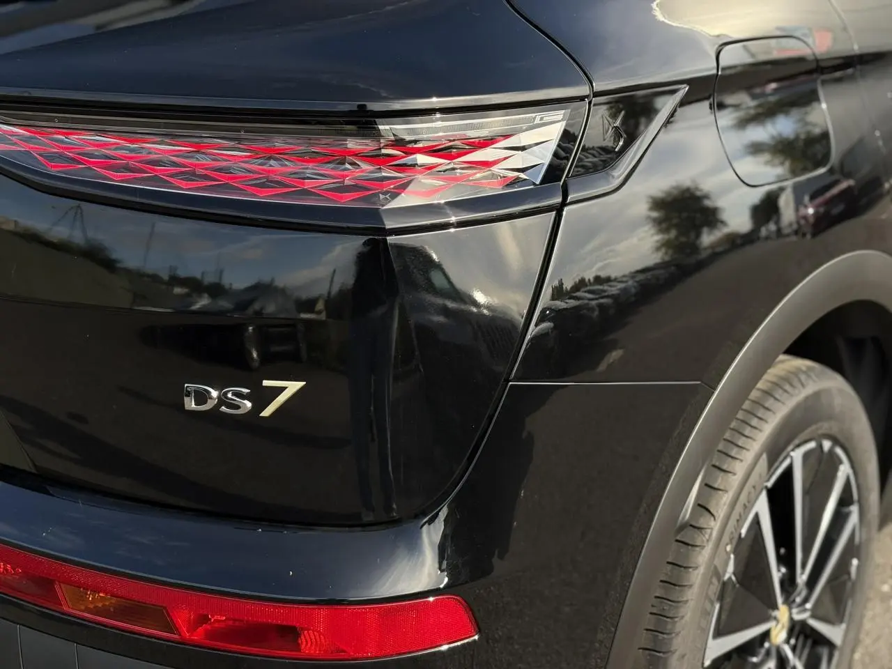 Gros plan sur l'arrière droit noir Perla du DS7 2025, mettant en valeur le feu arrière 3D et le logo DS7.