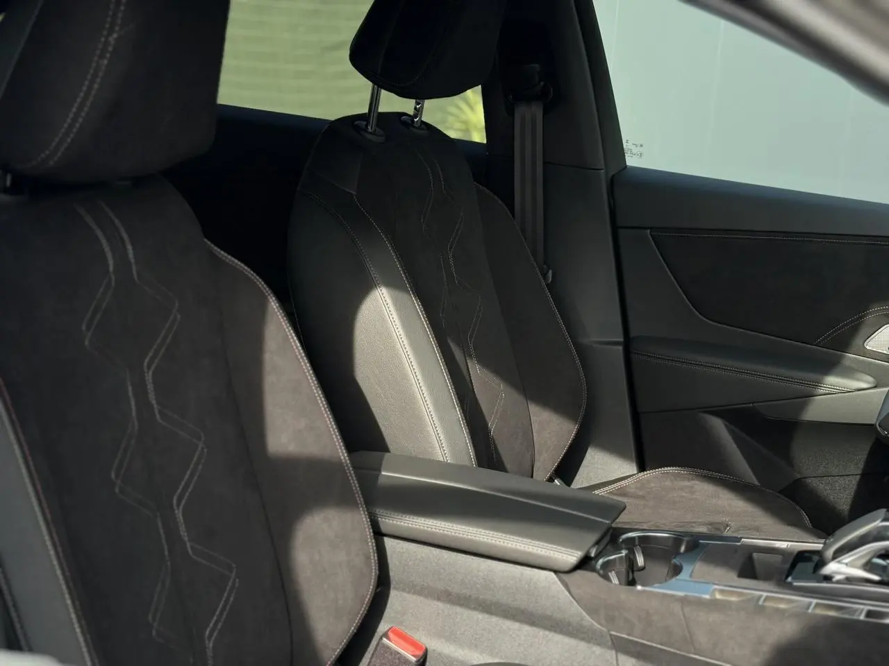 Vue intérieure des sièges avant en Alcantara noir profond avec surpiqûres Carmin et Or du DS7 2025.