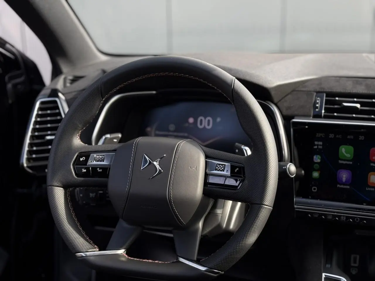 Volant en cuir noir perforé avec surpiqûres Carmin et Or du DS7 2025, tableau de bord et écran tactile visibles.